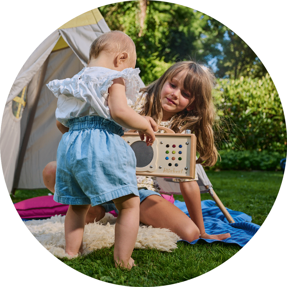 Two sisters are playing outside next to the hörbert speaker